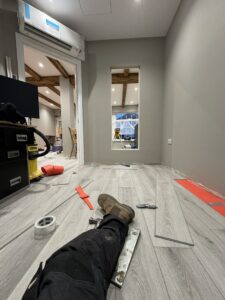 Fitter laying plank flooring over red underlay